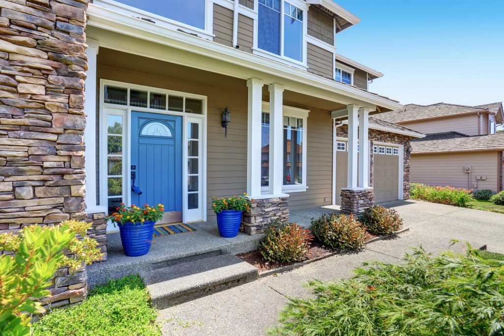 The front of a beige house with a blue door.