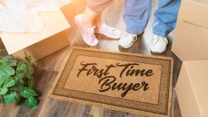 a couple's feet standing behind a floor mat that says "First-Time Buyers"